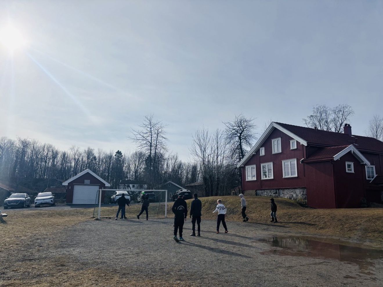 En gruppe mennesker som leker på en jordmark ved siden av et hus En gruppe mennesker som leker på en jordmark ved siden av et hus