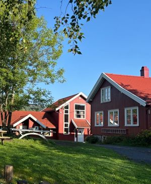 et rødt hus med en plen foran seg
